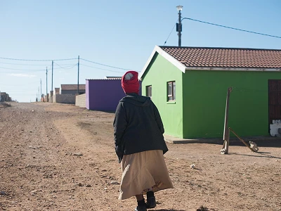 A woman walking through a township neighborhood.