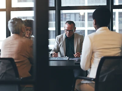 Group of investors engaged in discussion around a conference table.