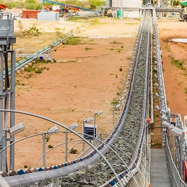 A large conveyor belt descends a hill in an industrial mining site, transporting materials efficiently.